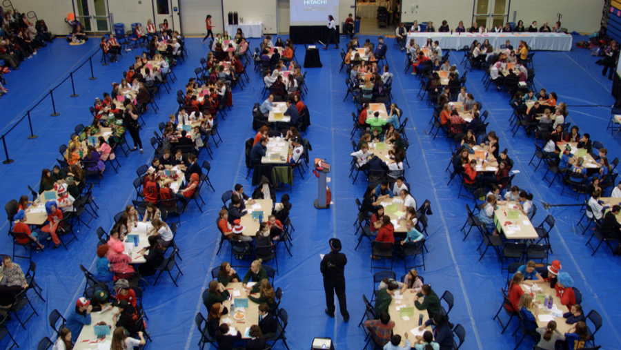 Six rows of tables hold dozens of students intent on their quiz papers